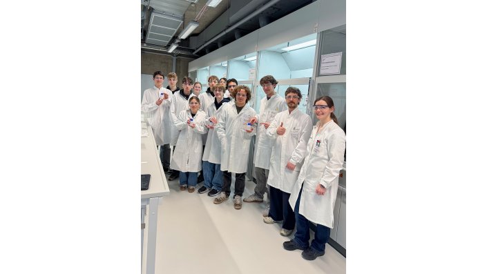 Der Chemie-Leistungskurs des Friedrich-Wilhelm-Gymnasiums steht mit Kitteln und Brillen im Labor.
