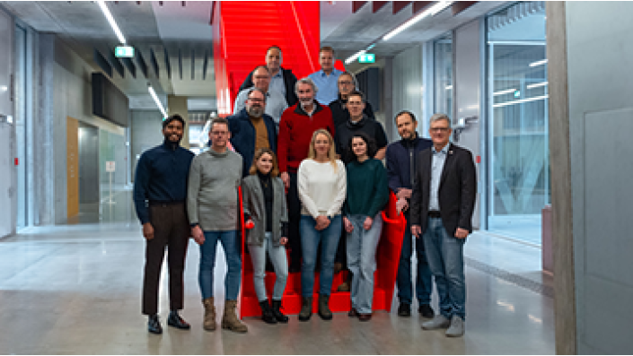 Die Projektpartner von Aquasan stehen im Flur des Campus Leverkusen vor der roten Treppe.