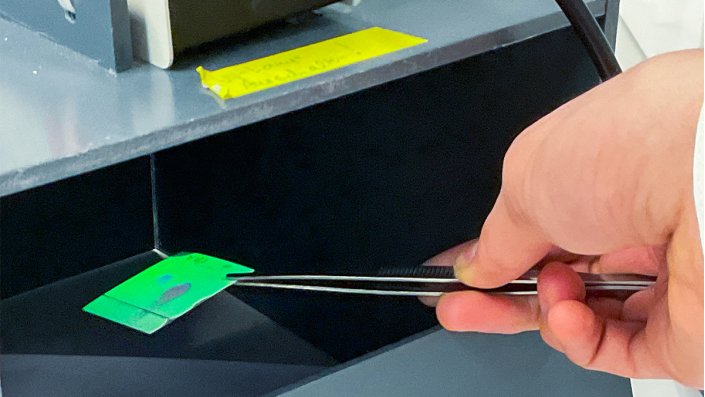 Ein Schüler hält eine DC-Platte unter die UV-Lampe, sie leuchtet grün