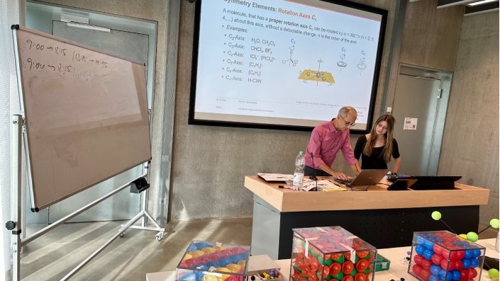 Prof. Dr. Dirk Burdinski und Magdalena Kroll stehen am Pult im Hörsaal und schauen auf das Tablet.