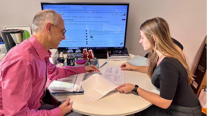 Prof. Dr. Dirk Burdinski und Magdalena Kroll sitzen am Schreibtisch und besprechen die anstehende Vorlesung. 