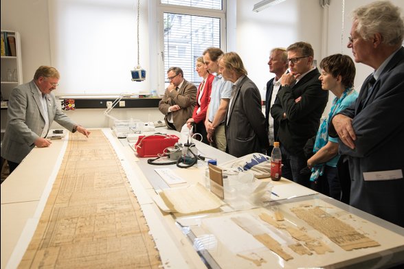 Prof. Dr. Robert Fuchs erklärt Besuchern etwas an einem Papyrus.