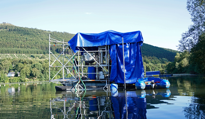 Eine schwimmende Plattform, an der ein Hochdrucksauger installiert ist, fährt kontinuierlich und weitestgehend automatisiert über einen Stausee. Dabei werden die Sedimente aufgewirbelt und zusammen mit dem Methangas aufgenommen.