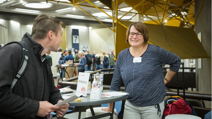 Am Infostand des Familienservice stehen zwei Menschen