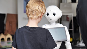 Ein Kind steht vor einem humanioden Roboter. (Bild: Foto: MKW NRW)