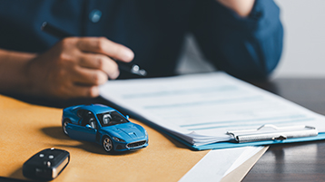 Ein Mensch unterschreibt ein Dokument. Daneben steht ein Spielzeugauto. (Bild: JD8 / AdobeStock.com) Ein Mensch unterschreibt ein Dokument. Daneben steht ein Spielzeugauto. (Bild: JD8 / AdobeStock.com)
