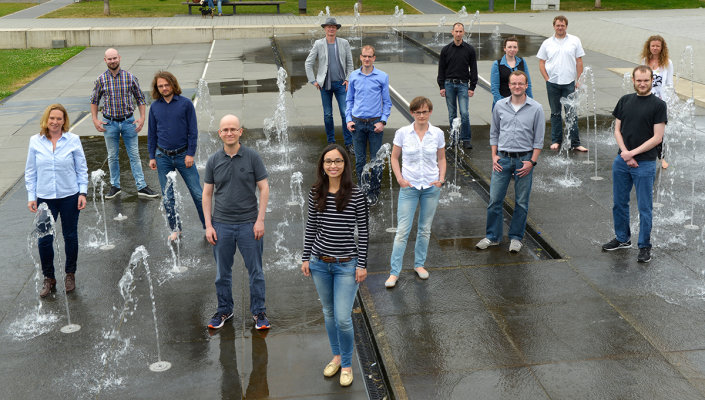Das Team des SPOTSeven Lab mit Prof. Dr. Thomas Bartz-Beielstein steht zwischen den Fontänen eines Springbrunnens.