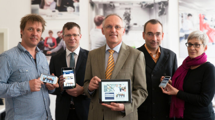 Hochschulpräsident Prof. Dr.-Ing. Christoph Seeßelberg und Projektverantwortliche zeigen die neuen Internetseiten auf Handy und Tablet