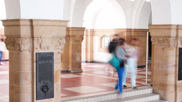 Foyer Ubierring 48, Treppenstufen, Säulen und Studierende (Bild: Dirk Osterkamp)