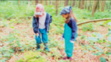 Zwei Kinder stehen im Wald und betrachten den Waldboden und zeigen auf etwas. Sehr verpixeltes/gekacheltes Bild. (Bild: Kathrin Meiners)