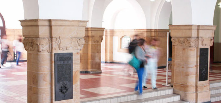 Foyer Ubierring 48, Treppenstufen, Säulen und Studierende (Bild: Dirk Osterkamp)