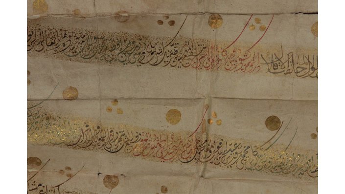 Bild 3 zeigt eine Detailaufnahme der arabischen Schrift, welche in schwarz und rot niedergeschrieben ist. Zudem ist das Schriftbild goldfarben verziert.