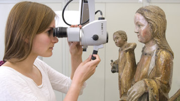 Eine Studierende untersucht mit dem Stereomikroskop eine Skulptur der Heiligen Maria mit dem Kind. (Bild: TH Köln - CICS) Eine Studierende untersucht mit dem Stereomikroskop eine Skulptur der Heiligen Maria mit dem Kind. (Bild: TH Köln - CICS)