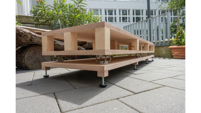 Das Bild zeigt den Sockel im "Rohbau". Er besteht aus dem Basisbrett mit justierbaren Möbelfüßen, den sechs Drahtseilfedern und dem Sockelkorpus mit dem Zwischenraum für die Einlegegewichte.