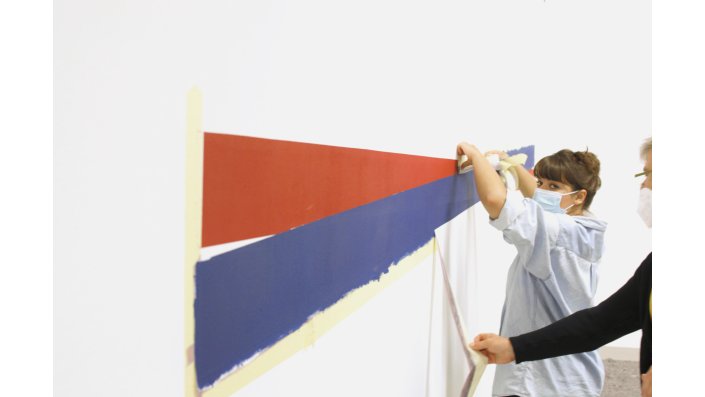 Zur Fertigstellung der Wandmalerei "Diskrete Überkreuzung Blau/ Rot IV" von Reiner Ruthenbeck werden die Klebebänder entfernt.