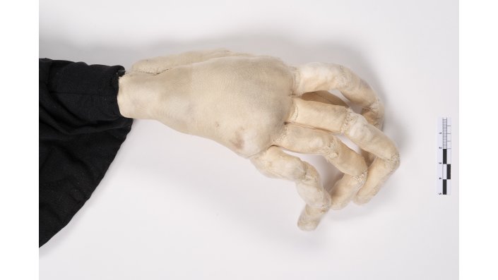 Detailaufnahme einer sehr fein- und langgliedrigen textilen Hand. Die Hand besteht aus einzelnen, aus Seide genähten Fingergliedern, die mit Watte gefüllt sind.