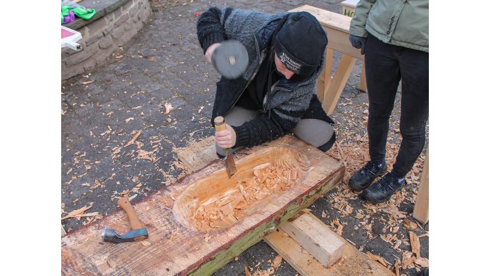 In ein Halbrundholz wird mit einem kleinen Dechsel und einem Stechbeitel eine Vertiefung ausgehöhlt. Am Ende soll eine "Molle" - norddeutsch für "Mulde" in der Bedeutung eines Backtrogs - entstehen.