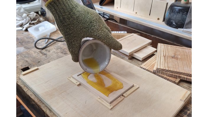 Im Rahmen eines Vorversuchs wird erhitztes Wachs in die Aussparung des Holzträgers gegossen.
