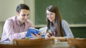 Studenten im Gespräch im Vorlesugnsraum, Tafel groß im Hintergrund Studenten im Gespräch im Vorlesugnsraum, Tafel groß im Hintergrund