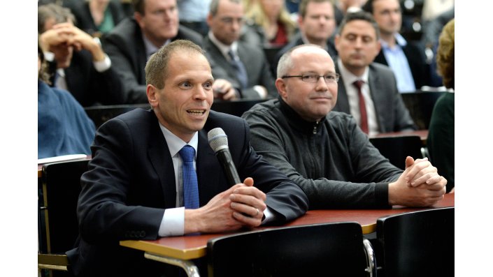 Ein Teilnehmer des Symposiums stellt eine Frage an das Podium