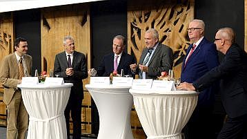 Die 5 Podiumsdiskussionsteilnehmer sowie der Moderator stehen auf der Bühne der Aula um Stehtische gruppiert (Bild: ivwKöln / TH Köln / Gerhard Richter)