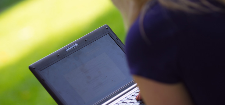 Eine Studentin sitzt mit einem Laptop im Park (Bild: Costa Belibasakis/TH Köln)