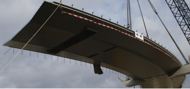 Eine Straßenbrücke hängt am Kran und wird gerade in die richtige Position gehoben (Bild:Bilfinger Berger AG)