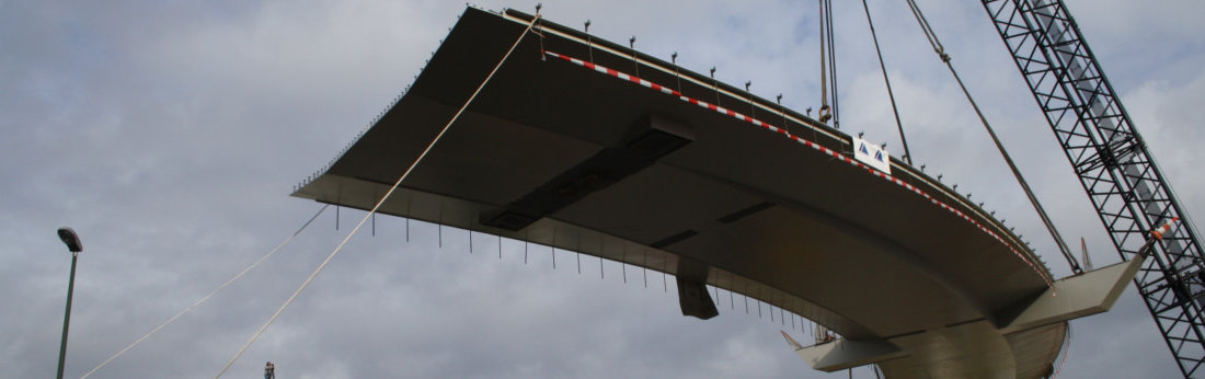 Eine Straßenbrücke hängt am Kran und wird gerade in die richtige Position gehoben (Bild: Bilfinger Berger AG)