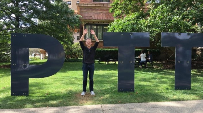 Lennart Böhm steht vor dem Logo der University of Pittsburgh