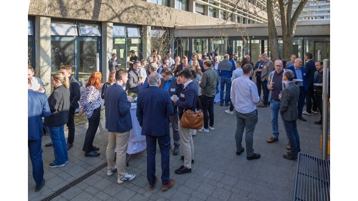 Eine große Menschengruppe steht in der Pause im Atrium des Altbaus