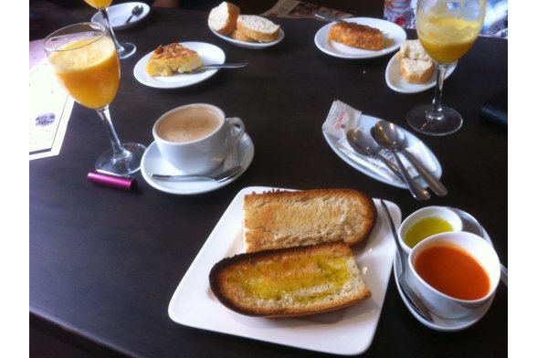 Getoastetes Baguette mit Olivenöl und Tomate, ein Kaffee mit Milch und ein frisch gepresster Orangensaft