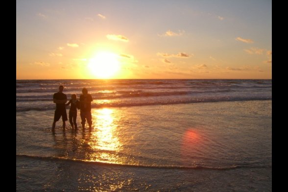 Drei Menschen im Sonnenuntergang am Strand
