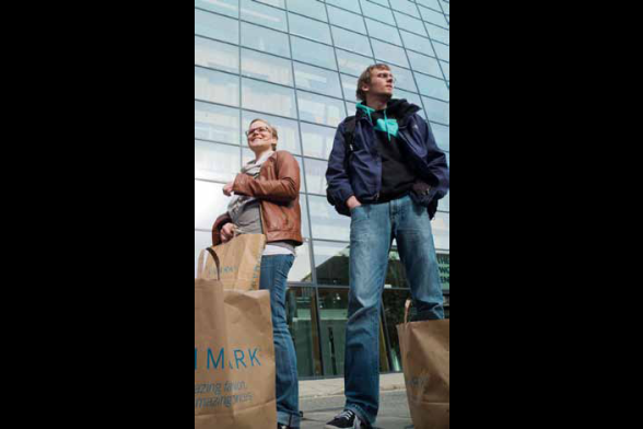 Zwei junge leute mit Einkaufstüten vor einer Glasfassade