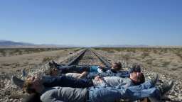 Vier junge Männer liegen quer über ein Gleis in endloser Prärie (Bild: Arno Daniel)
