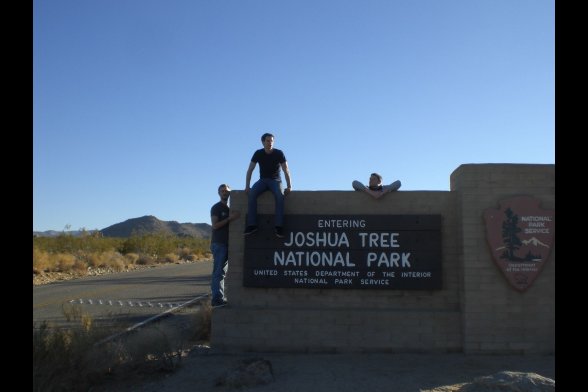 Drei junge Männer vor dem Einga<ngsschild zum Joshua Tree National Park 