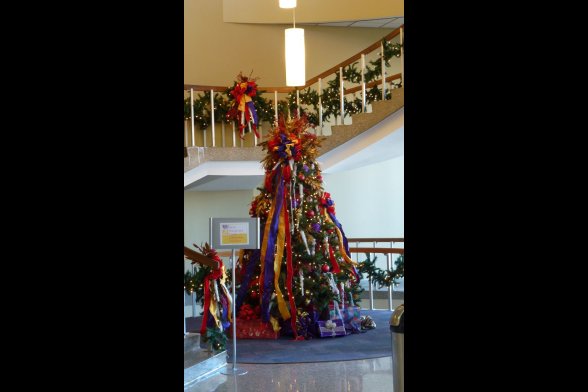 In einem Treppenhaus steht ein mit bunten Bändern und kleinen Lichetren geschmückter Weihnachtsbaum