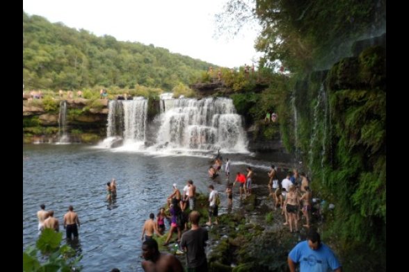 Menschen baden in einem See, der von Wasserfällen gespeist wird