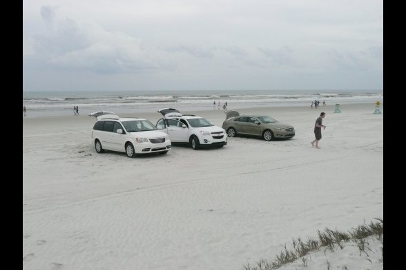 Blick auf drei Autos und Menschen am Strand