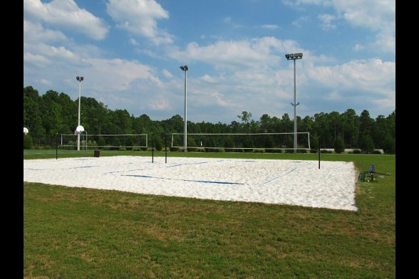 Wiese mit Flutlicht und Beachvolleyball-Feld