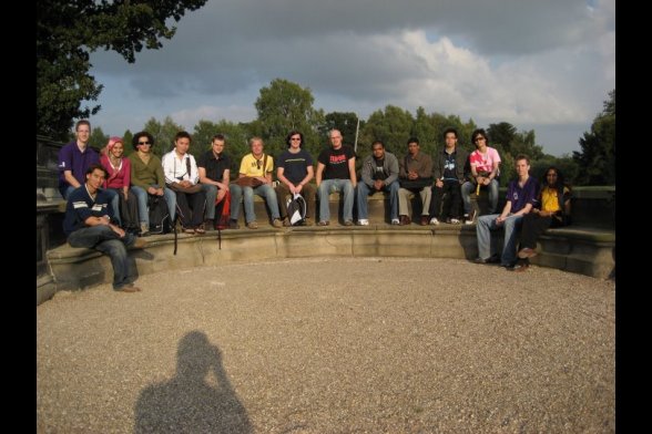 Junge Menschen sitzen im Halbkreis auf einer Steinmauer