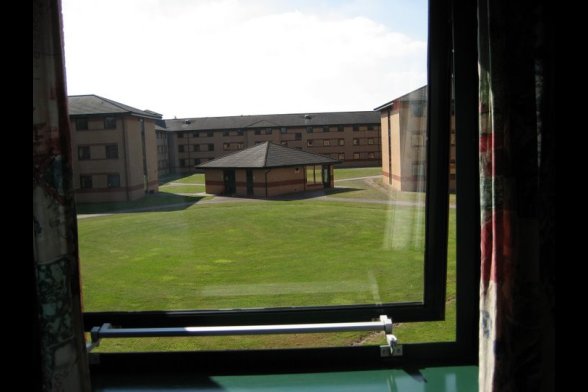 Blick aus einem Fenster auf eine von Gebäuden umgebene Grünfläche