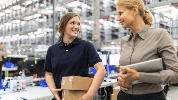 Zwei Personen gehen durch ein Lager. (Image: alvarez/istock.com)