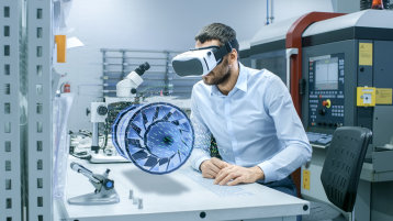 Mann mit Kopfhörer und Turbine auf dem Tisch vor ihm (Bild: gorodenkoff/istock.com)