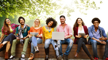 Junge fröhliche Menschen sitzen auf einer Bank (Image: iStock)