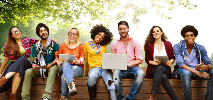 Junge fröhliche Menschen sitzen auf einer Bank (Image: iStock)