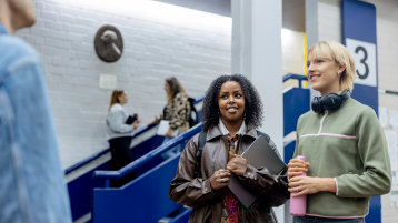 Zwei weiblich gelesene Studierende stehen vor einem Hörsaal (Bild: Hanna Witte/TH Köln)