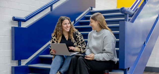 Zwei weiblich gelesene Studierende sitzen mit einem Laptop und einem iPad auf einer Treppe (Bild:Hanna Witte/TH Köln)