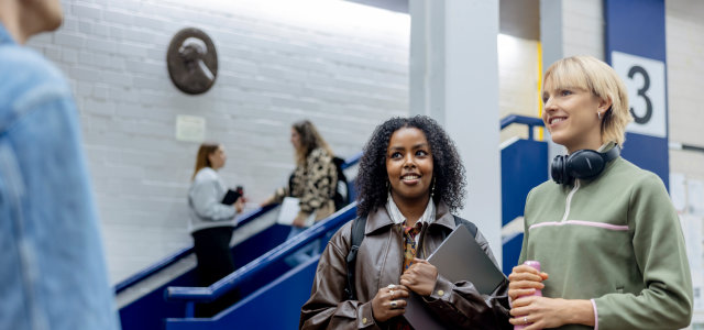 Zwei weiblich gelesene Studierende stehen vor einem Hörsaal (Bild:Hanna Witte/TH Köln)