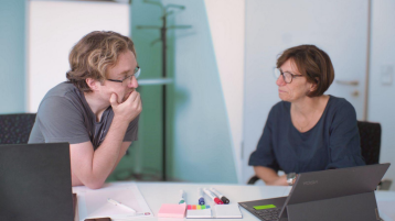 2 Personen sitzen am Schreibtisch 2 Personen sitzen am Schreibtisch