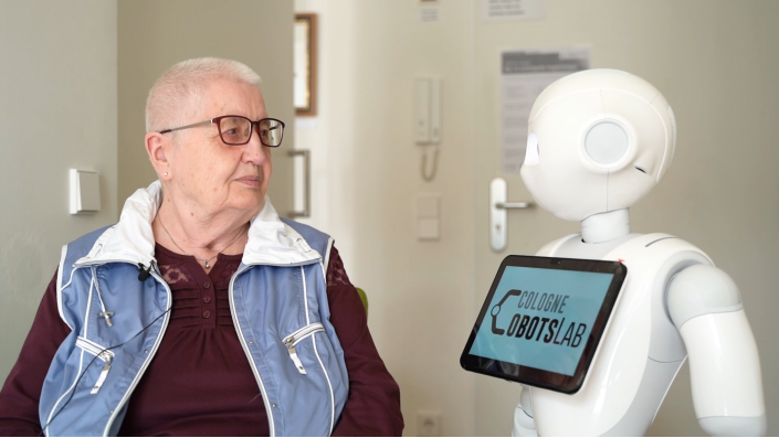 Eine Dame spricht mit Pepper dem Roboter